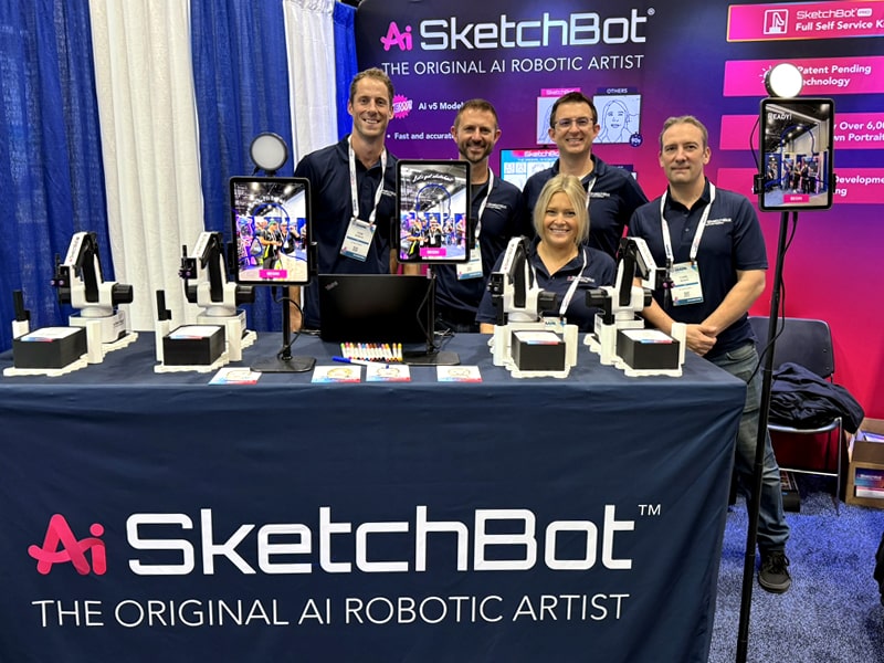 The Picture Mosaics team standing at the SketchBot table at IAAPA